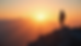 Eye-level view of a person standing on a mountain peak at sunrise, symbolizing personal growth and reflection